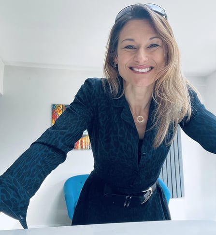 Caroline Muldoon, menopause coach, leaning on desk in business attire