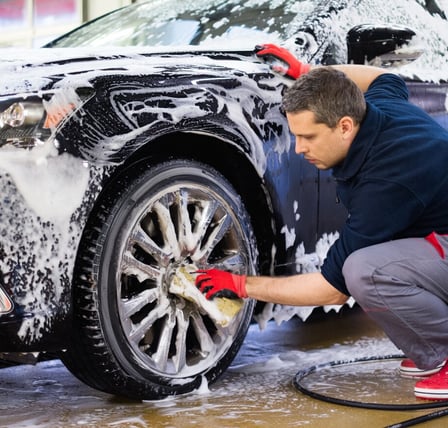 a man washing a car with foam foam