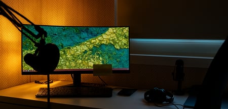 a desk with a computer monitor and a microphone