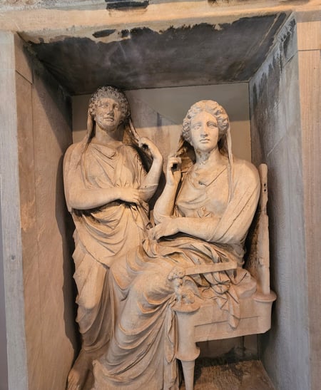 two ancient Greek statues of women, displayed in a museum in Athens