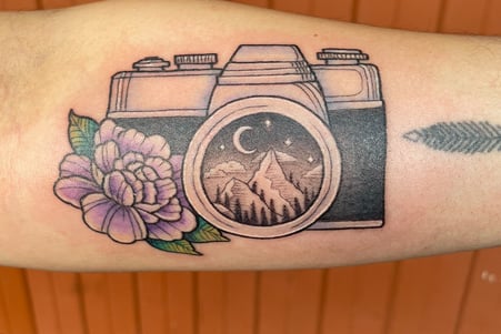 Tattoo of camera with a mountain scenery and flower