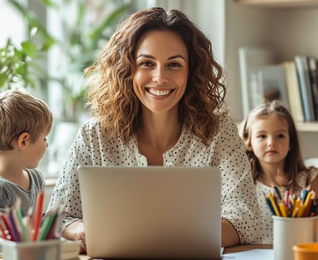 Mujer sonriente trabaja en laptop acompañada de niños, representa emprendimiento desde casa, mujer, hijo, equilibrio familiar