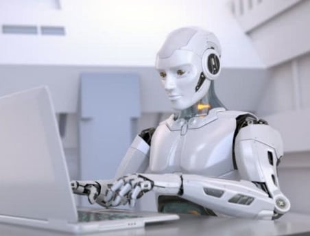 a robot is sitting at a desk with a laptop