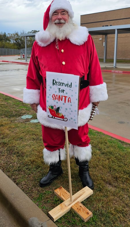 The Santa Cowboy standing behind his "reserved " parking sing at Spring Creek Elemtary school visit