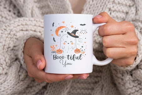 a person holding a mug with a halloween themed mug