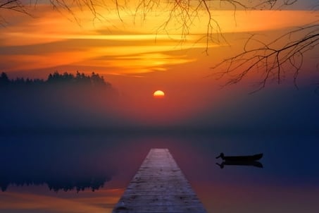 Coucher de soleil sur un lac avec une barque et une avancée en bois
