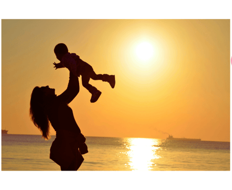Photo montrant une mère soulevant son enfant sur fond de coucher de soleil