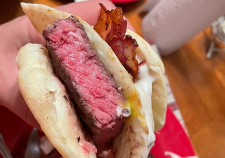 Rare steak served on a biscuit with egg and bacon