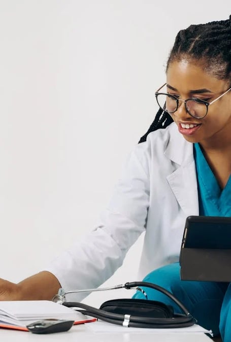 a woman in a lab coat and glasses is holding a tablet computer