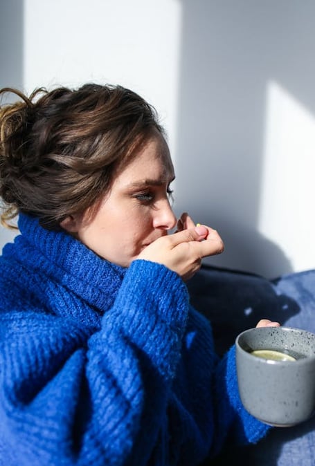 a woman in a blue sweater is holding a cup of coffee