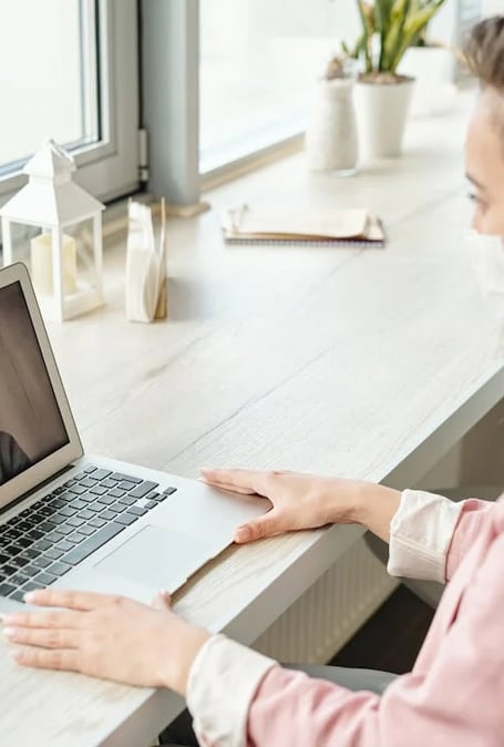 a woman in a pink shirt is sitting at a desk with a laptop