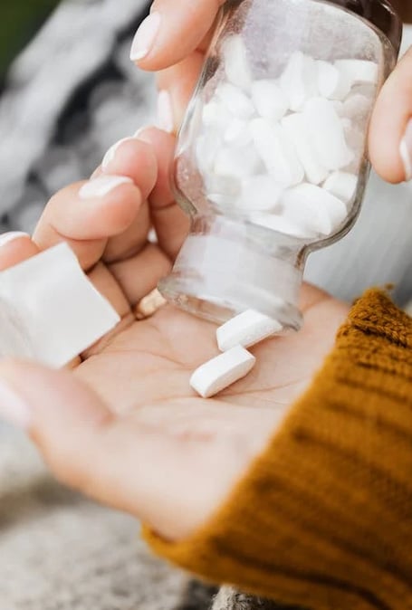 a person holding a jar of pills and pills