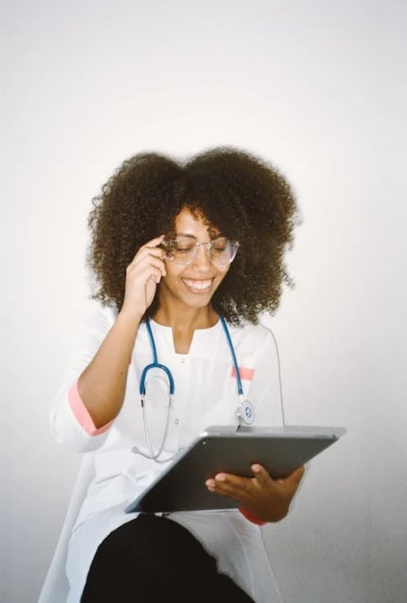 a woman in a white lab coat and glasses talking on a cell phone