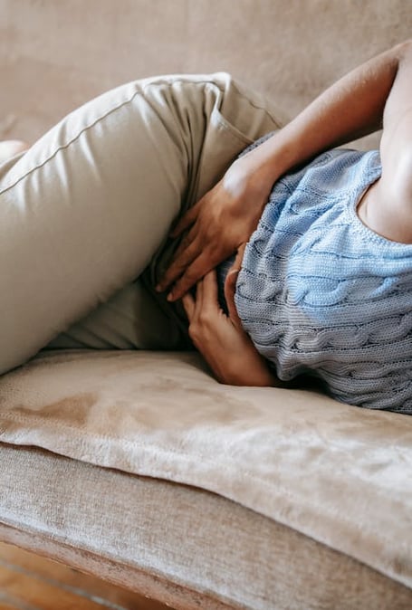 a woman laying on a couch with her hands on her stomach