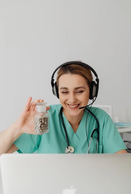 a nurse in a green scrub scrubsuit with a jar of pills