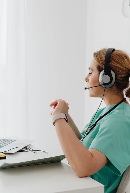 a woman in a green shirt and headphones is sitting at a desk