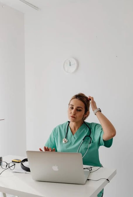 a woman in a green scrub suit sitting at a desk