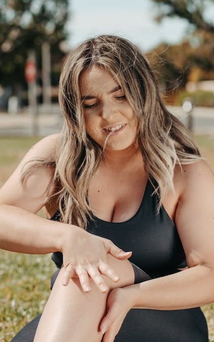 a woman in a black swimsuit sitting on a bench in the grass