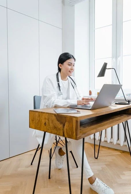 a woman in a white lab coat and a stethoscope on a desk