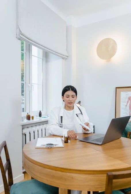 a woman in a white lab coat is sitting at a table