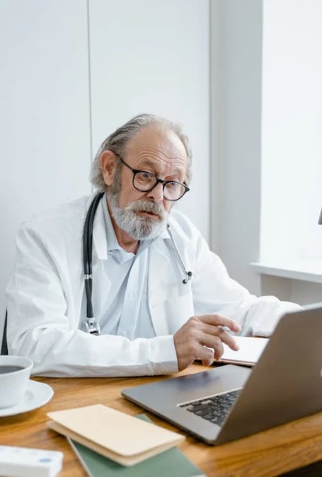 a man in a lab coat and glasses sitting at a desk