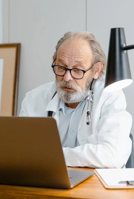 a man in a lab coat and glasses is sitting at a desk