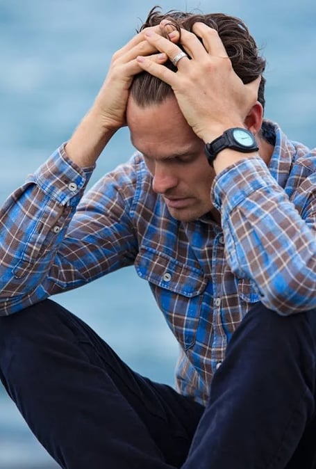 a man sitting on a bench with his hands on his head