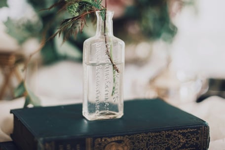 Bouteille en verre contenant une plante posée sur un livre ancien