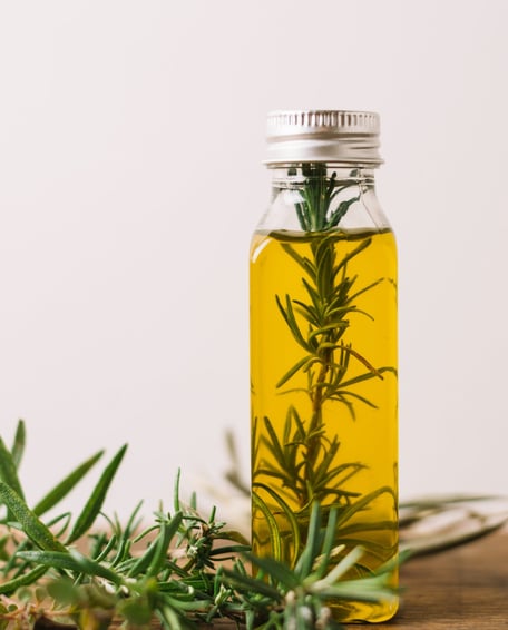 a bottle of olive oil with rosemary sprigs kannauj pickupwale