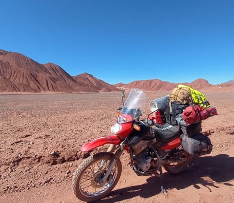 a motorcycle parked in the desert with a backpack on it cono de arita puna atacama salar