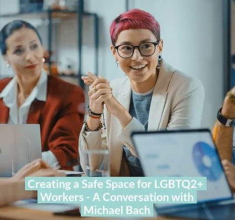 Image of a woman with red hair seated at a meeting, next to another woman, laptops open