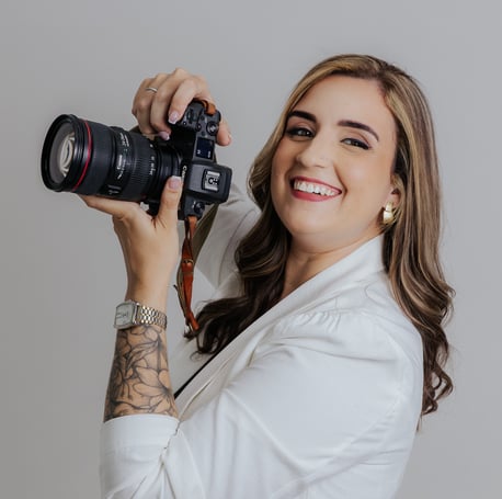 a woman holdingDébora Oliveira fotógrafa de casamentos no Rio de Janeiro a camera and smiling