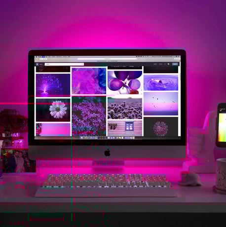 A stylish desk setup with a computer displaying a gallery of images, highlighting web design inspiration.