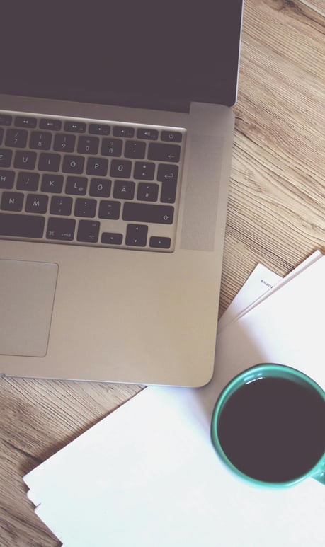 Une tasse de café et un PC sur bureau pour illustrer la page Contact de Kreskin