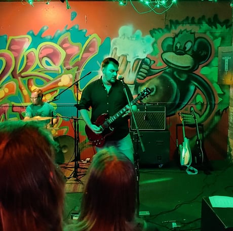 John onstage preforming with green background