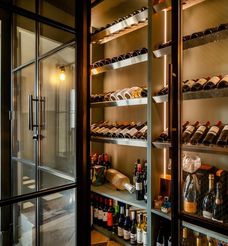 Contemporary wine cellar at Villa La Gratitud with glass doors, backlit shelves, and wine collection
