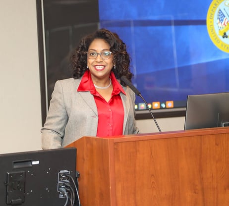 Rosalyn Cousins a woman in a suit and glasses standing at a podium