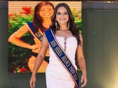 a woman in a white dress and a blue sash sash
