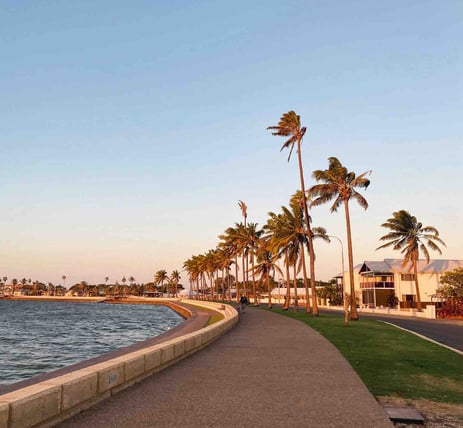 Peaceful walk between the water and coconut trees at sunset in Carnarvon, Western Australia.