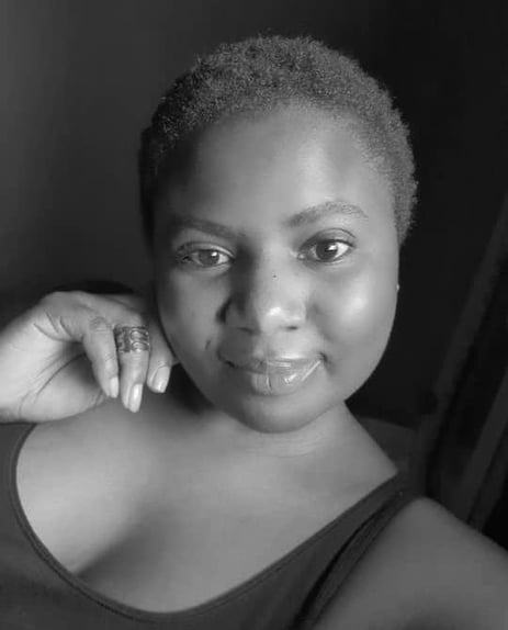 a woman with a hand on her jaw smiling at he camera