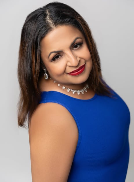 A woman wearing a blue dress with a soft smile.