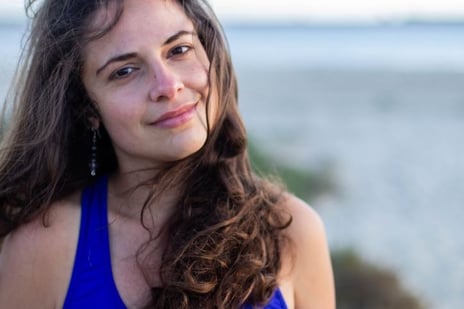 a woman in a blue tank top and earrings