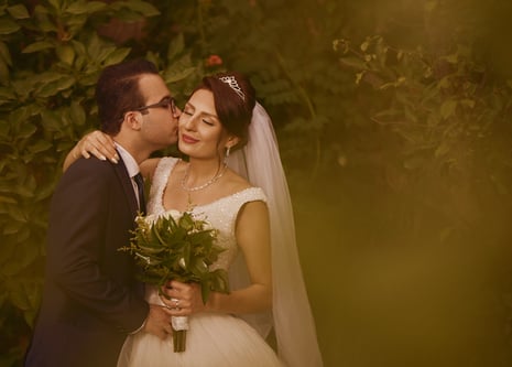 a bride and groom kissing in a garden