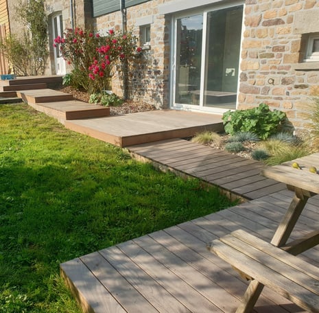  Terrasse en bois composite avec accès en pas japonais, installée le long d'une maison en pierre