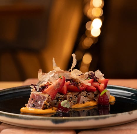 Fotografía profesional de un tataki de atún con ckatsobushi, fresas y una cama de una salsa deliciosa, .