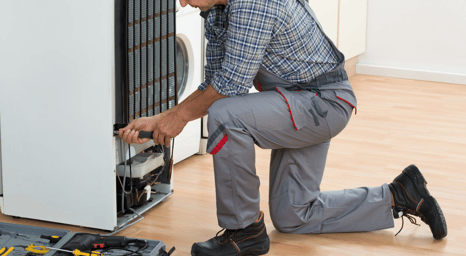 a man in a plaid shirt and pants is fixing a dishwasher
