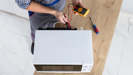a man in a blue apron and a white shirt is holding a multimetered