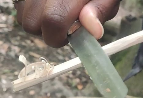 a person holding a knife in their hand carving green wood