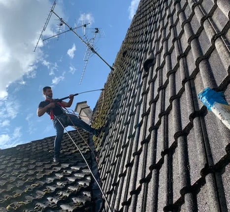Artisan couvreur en intervention sur une toiture, effectuant un nettoyage haute pression à Belfort, équipé de harnais de sécu