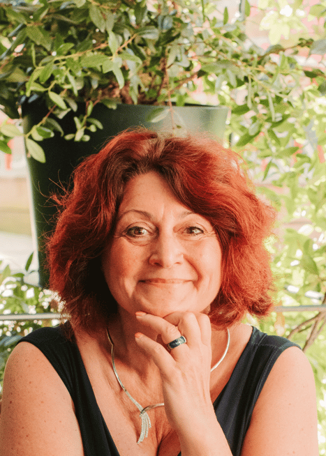 Flo Salort assise, main sous le menton, exprimant bienveillance, joie et leadership féminin